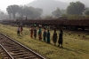 Passengers, having just alighted from 58101 0600 Tatanagar - Badampahar at Gorumahisani, walk by a loaded sleeper train as they make away with their loads on their heads